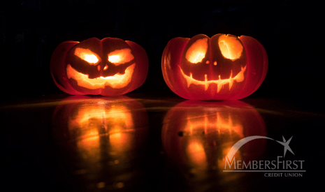 one happy and one scary orange pumpkin lit up in the dark