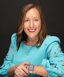 Photo of Ashley DuBois seated in a chair wearing a light teal dress